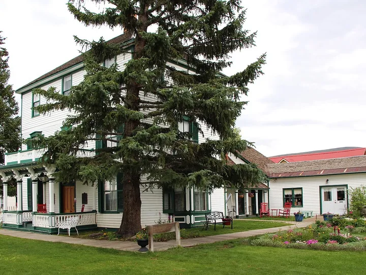 The white, green-trimmed Healy House in Leadville, with its porch, spruce trees and flower beds, in August 2015