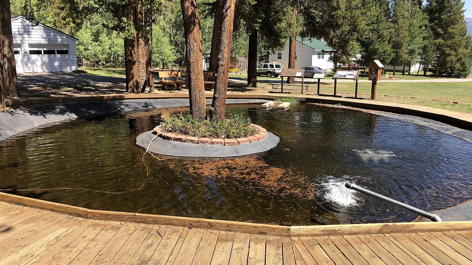 The round display pond with a boardwalk and interpretive signs at Leadville National Fish Hatchery, in September 2022