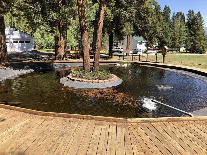 The round display pond with a boardwalk and interpretive signs at Leadville National Fish Hatchery, in September 2022