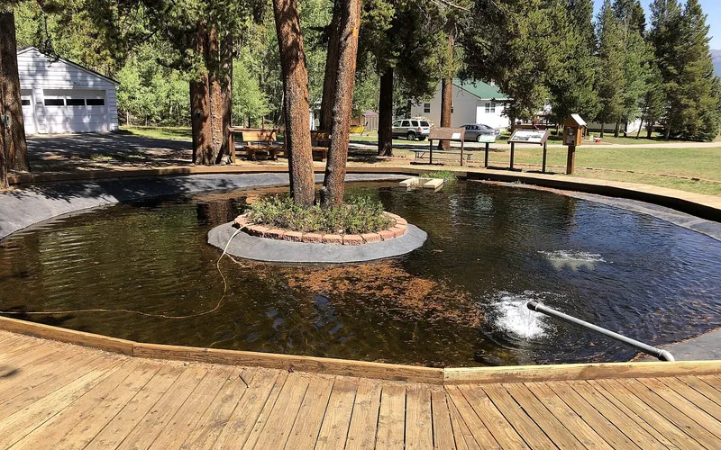 The round display pond with a boardwalk and interpretive signs at Leadville National Fish Hatchery, in September 2022