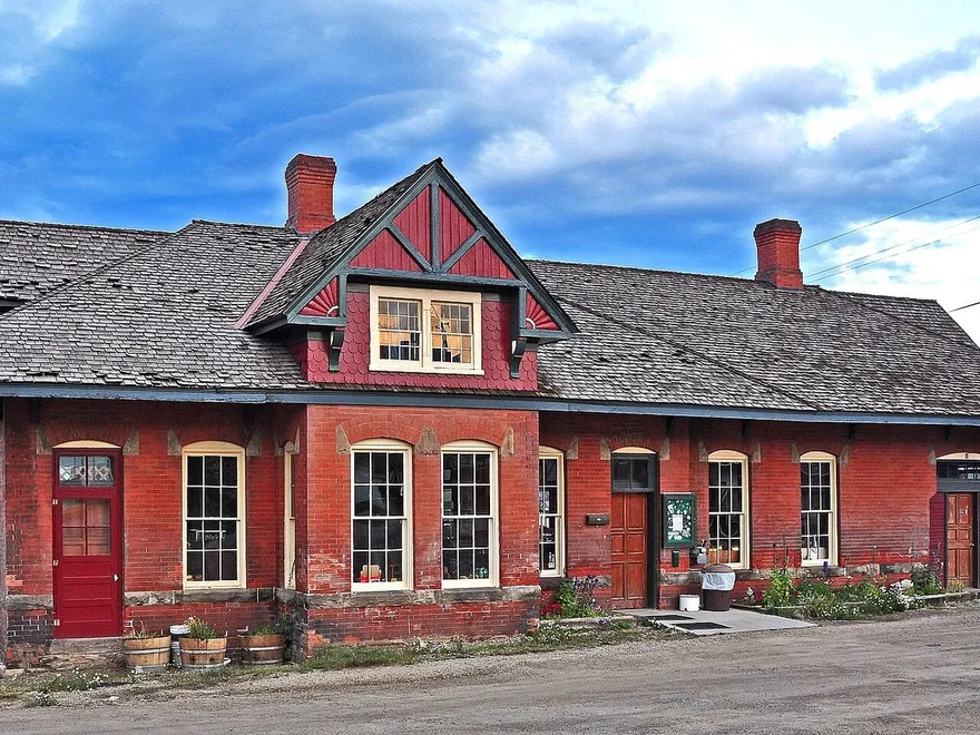 Leadville's red-brick railroad depot on East 7th Street, with a shingled roof, a half-timbered gable over the bay and tall arched windows, in August 2013